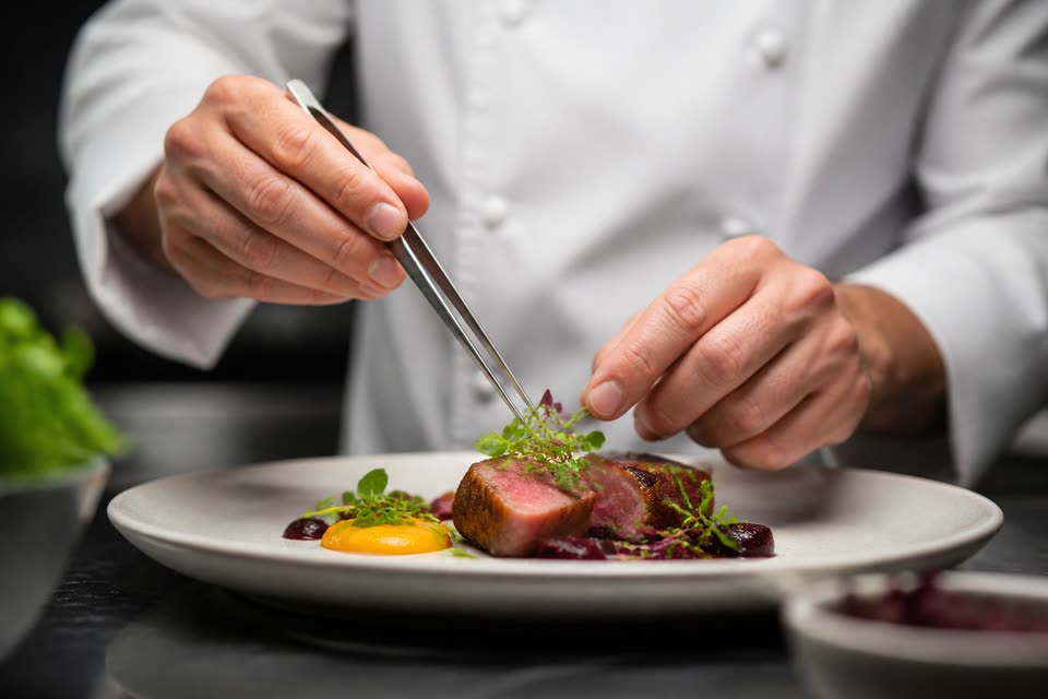 ピンセットで料理を仕上げるシェフの手元
